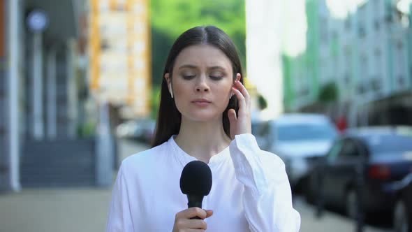 Serious Female Reporter With Microphone in Front of Camera, Breaking News