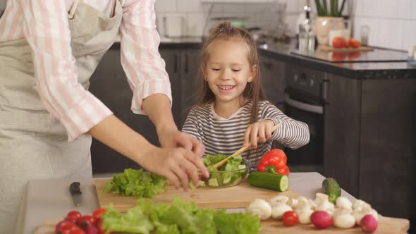 Little Girl Smiling Learning To Cook Vegetable Salad Kitchen Home Mother Helps Her Daughter Make