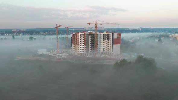 Construction site of a new high-rise building in the morning fog.