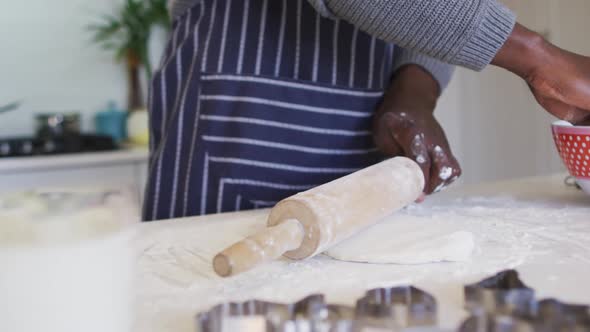 Hands of african american man using flour, preparing dough in kitchen
