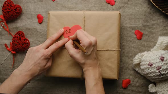 Hands Write Love Message on a Valentine's Day Card