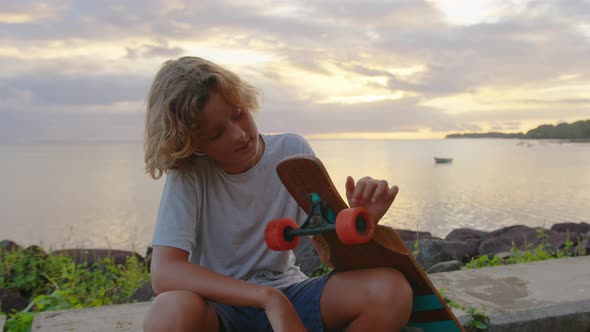 A Teenager Rides a Longboard Along a Beautiful Road with Green Palm Trees