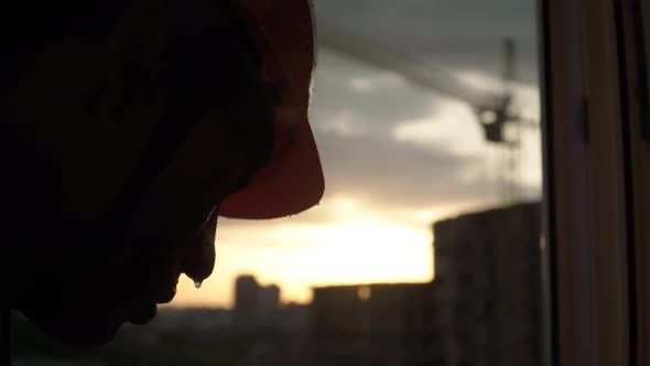 Portrait Dirty Sweaty Building Worker Smokes on Background Construction Crane and Beautiful Sunset