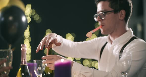 Young Attractive Man Removes a Label From a Bottle of Champagne That Would Open with a Pipetongue in