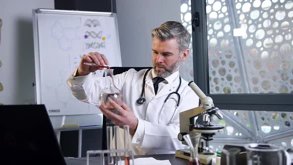 Male Doctor Doing Chemical Experiments with Liquids in Test Tube and Flask in Medical Lab