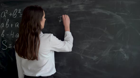 Math Teacher Writing Equation or Function on Blackboard in School Classroom