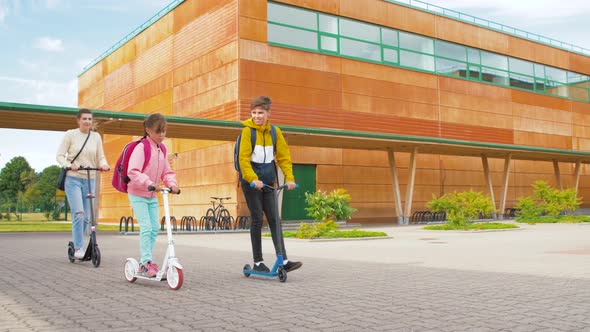 Happy School Children with Mother Riding Scooters