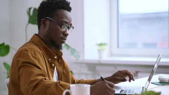 Afro Man Work at Laptop and Write Notes in Notebook Spbas