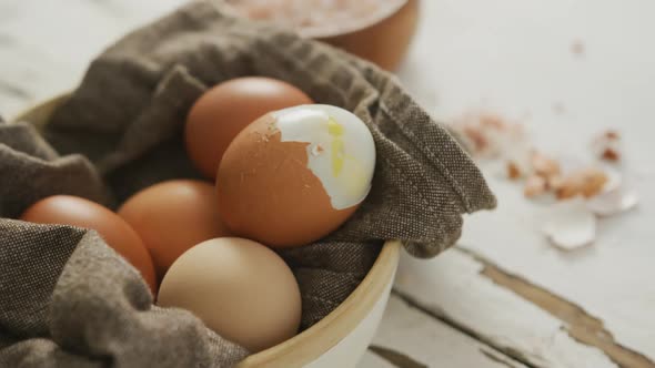 Video of close up of hard boiled brown eggs with cloth in bowl on rustic background