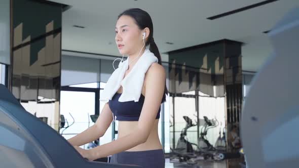 slow motion beautiful asian Sport women walk cool down on treadmill cardio equipment gym background