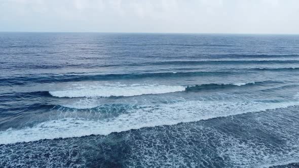 Aerial drone view of ocean waves washing over a beach