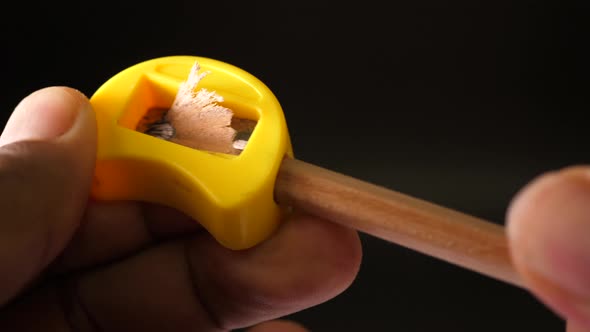 Sharpening a Pencil with a Sharpener on black background