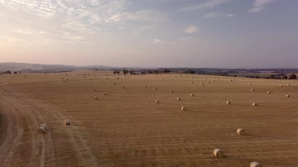 aerial view of harvested field with straw bales in sunset