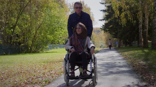 Woman on wheelchair with boyfriend at autumn park