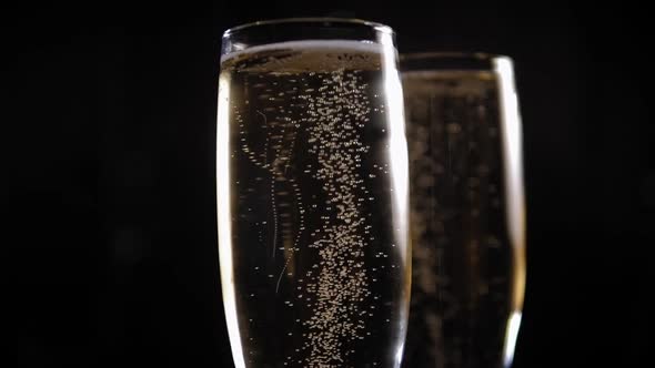 Two Glasses of Champagne on a Black Background with a Bokeh Slowly Rotating