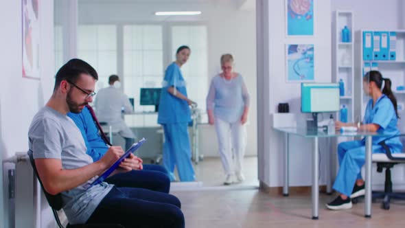 Man Filling Paperwork in Hospital Waiting Area