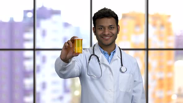 Happy Darkskinned Doctor Shows Can of Pills and Thumb Up