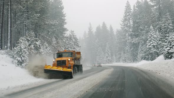 Passing snowplow car removing snow from the street