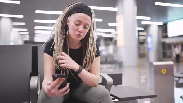 Attractive Young Woman Blogger with Dreadlocks Using Phone at the Airport