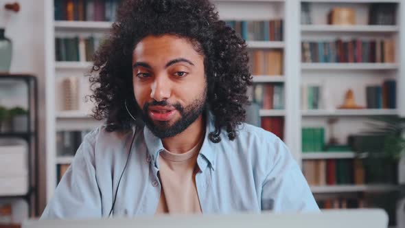 Young Arabian Man Call Center Employee in Headset Sits at Table with Laptop