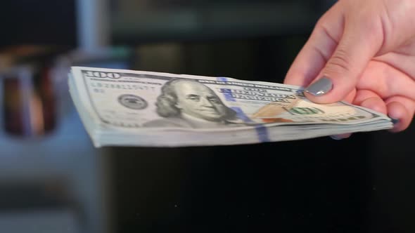 Girl Giving Lot of Dollar Bills in Hands of Man