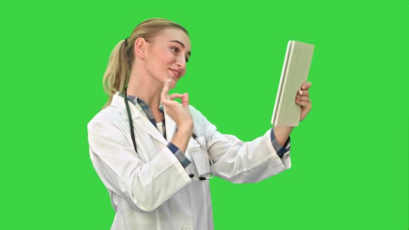 Happy Young Doctor Having Video Conference on Tablet with Patient on a Green Screen