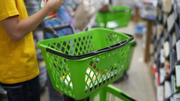 Boy choosing school supplies. Shopping cart with school supply