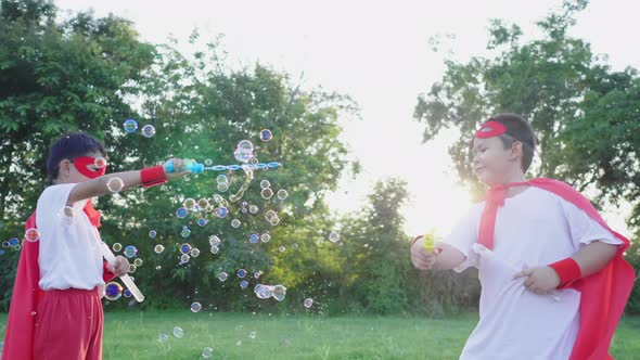 Happy Asian boys playing bubbles at the park