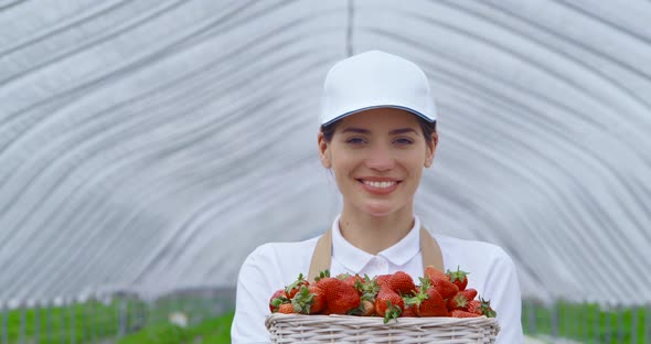 Woman in Cap and Apron Holding Basket with Strawberries
