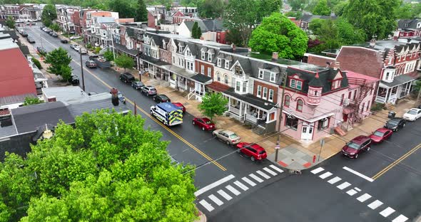 Aerial view of ambulance driving down city street. Overcast and rainy day. First responders drive to