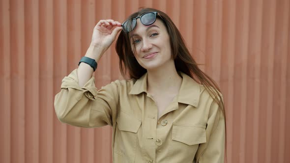 Portrait of Playful Young Girl Raising Glasses and Winking Standing Outdoors and Looking at Camera