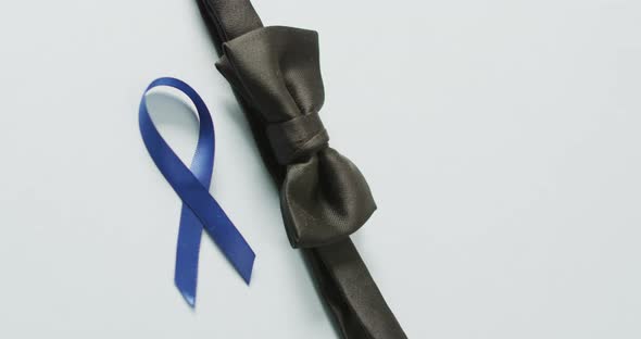 Video of black bow tie and dark blue colon cancer ribbon on pale blue background