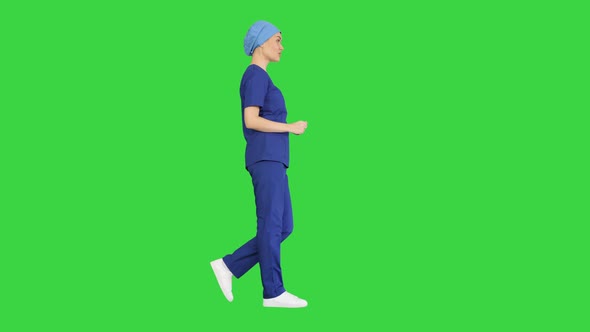 Smiling Female in Blue Medical Uniform Advertising Clinic Services While Walking on a Green Screen