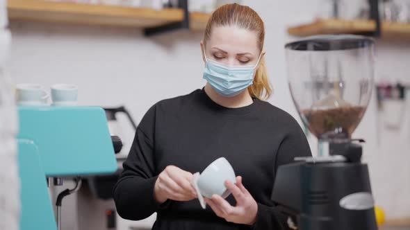 Concentrated Caucasian Woman in Covid19 Face Mask Cleaning Coffee Cup Before Making Hot Drink