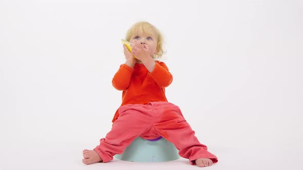 Adorable Cheerful Toddler Girl Sitting on Potty Talking on Her Smartphone
