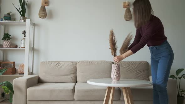 Young Woman Decorates Home Interior Puts Vase on Table and Sits on the Sofa to Relax