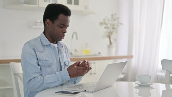 African Man with Laptop Having Wrist Pain at Home 