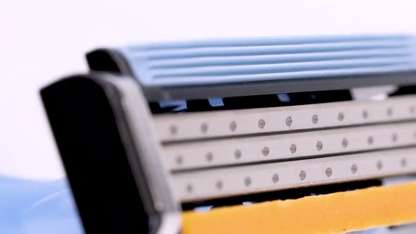 Macro shot of a disposable shaver razor blade rotating on white background, close up view on 4k.