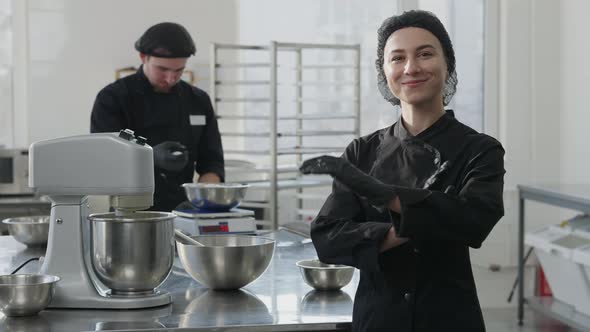 Portrait of Charming Confident Young Woman in Cook Uniform Crossing Hands Looking at Camera Smiling