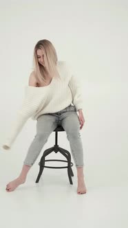 Smiling Woman Sitting and Posing on Chair in White Studio