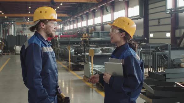 Male And Female Factory Workers Smiling And Shaking Hands