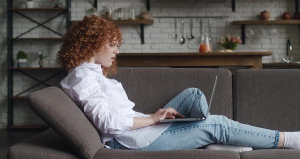 Side View of Upset Young Woman Looking at Laptop Screen and Reading Bad Message While Sitting on