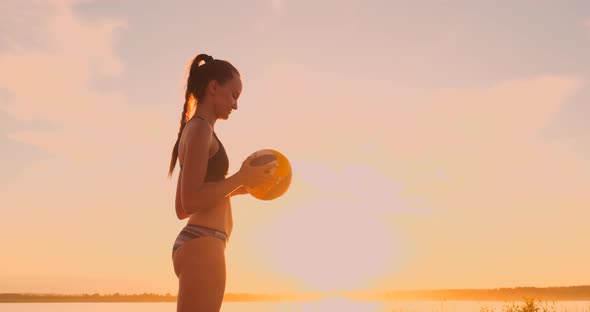 Athletic Girl Playing Beach Volleyball Jumps in the Air and Strikes the Ball Over the Net on a