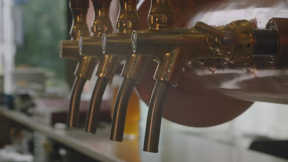Tilt up medium shot on a vintage brass, golden and wood beer pump inside a pub with blurry backgroun