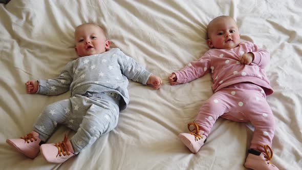 Two girls sisters lie on the bed. Two baby twins on the bed