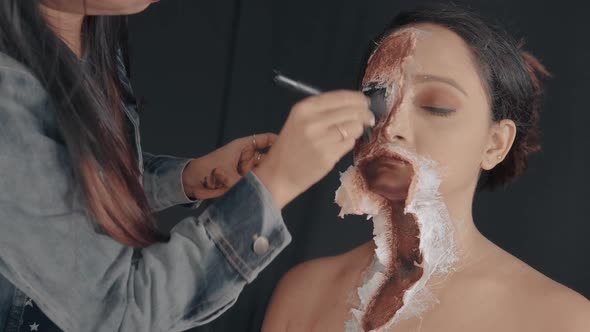 Professional make up artist making a scary and bloody mask on the woman's face
