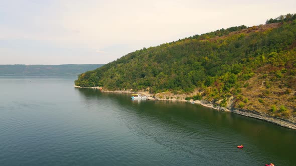 Above View of Picturesque Seashore and Sea Surface with Small Ship Mooring Ashore at Daytime