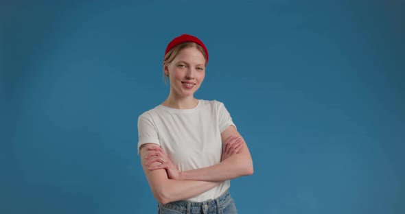 Young Female Smiling with Arms Crossed on Blue Background