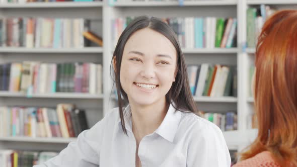 Charming Young Asian Woman Enjoying Studying with Her Friend at the Library