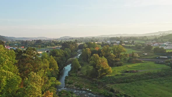 River with vegetation flowing parallel to highway in northern Spain with an idyllic sunset light.